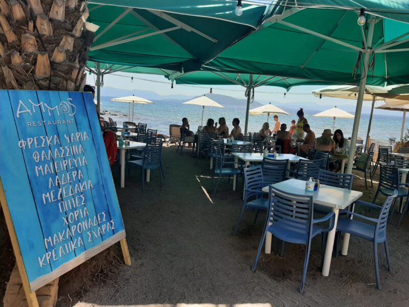 The terrace of the Ammos tavern, feet in the sand in Aegina