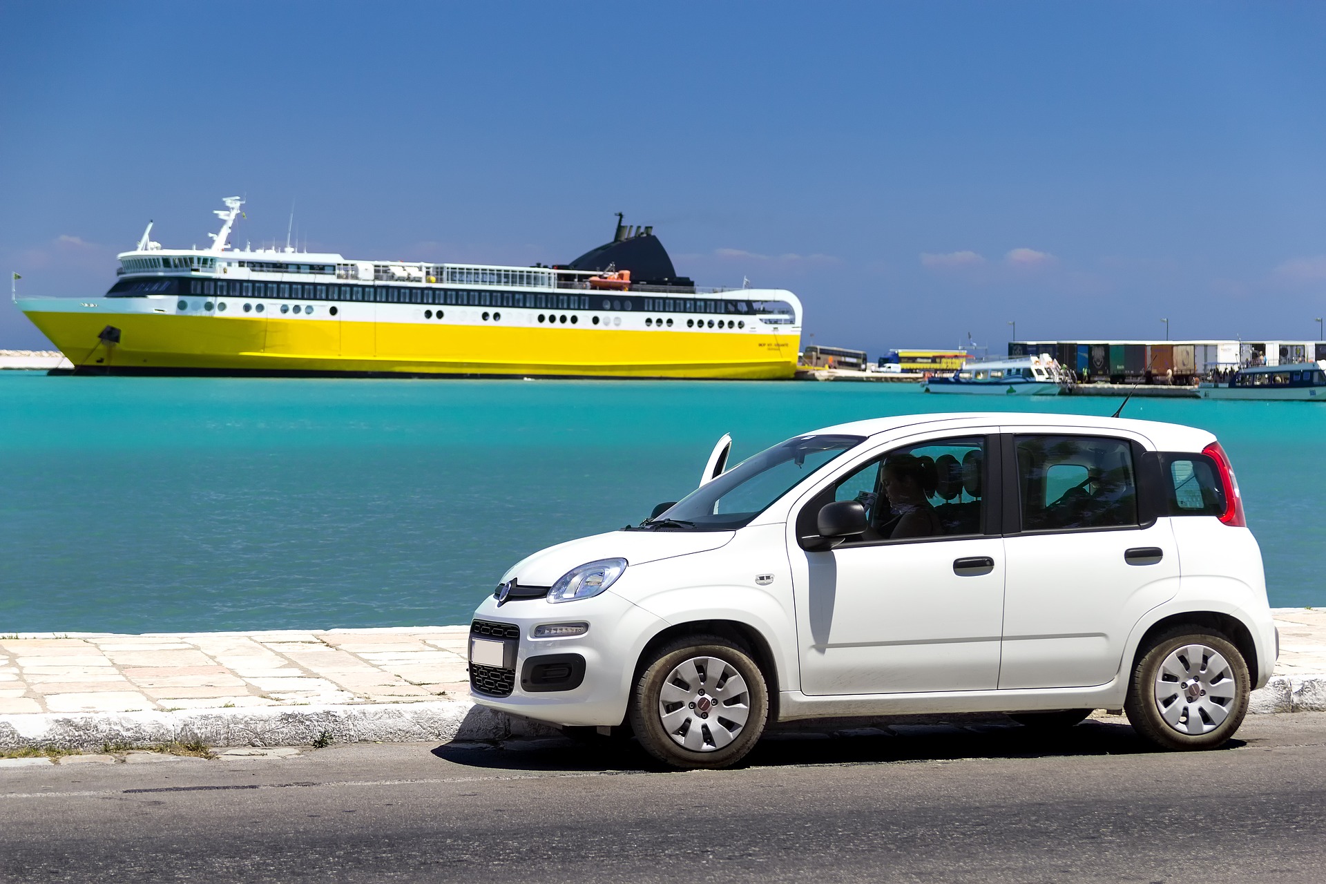 a car in front of a ferry, blue sea