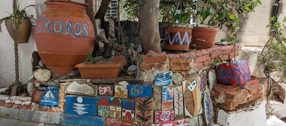 Painting on cobblestones and clay pots on a street in Ikaria